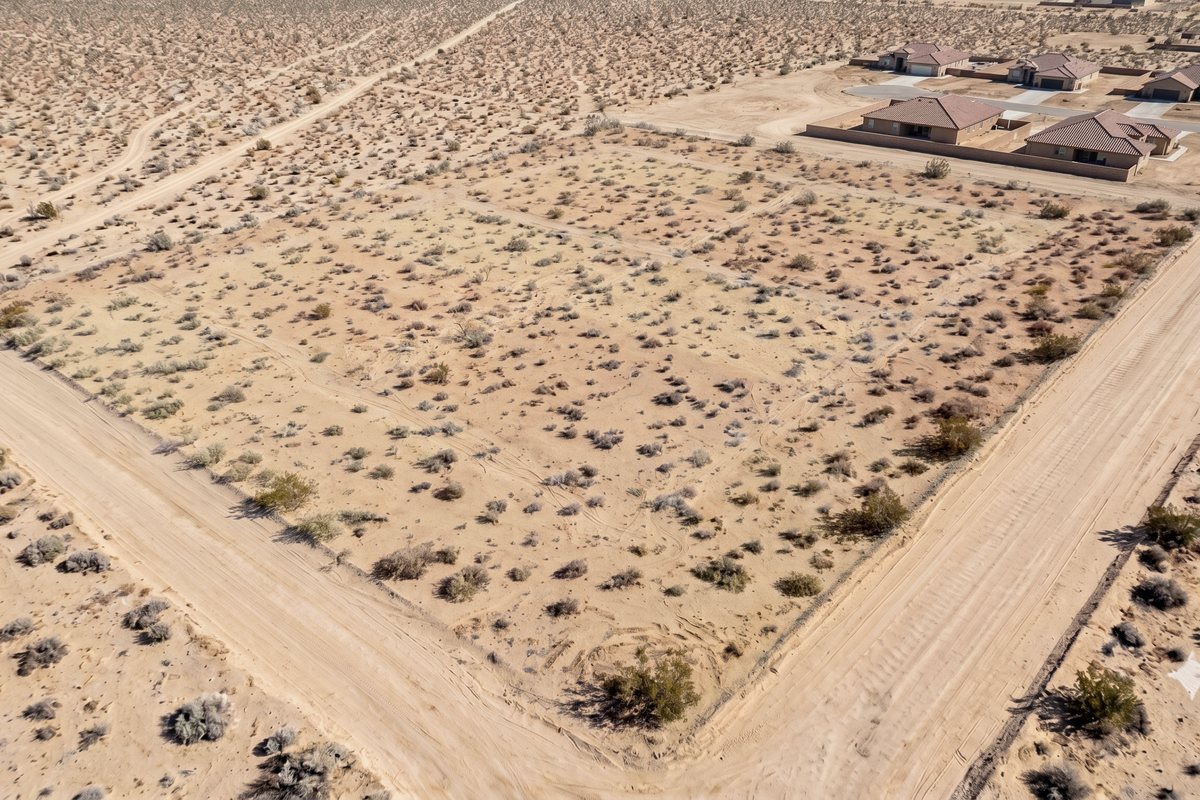 Aerial view of the flat vacant desert parcel before development, bounded by dirt section roads